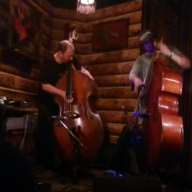 Two men playing double basses